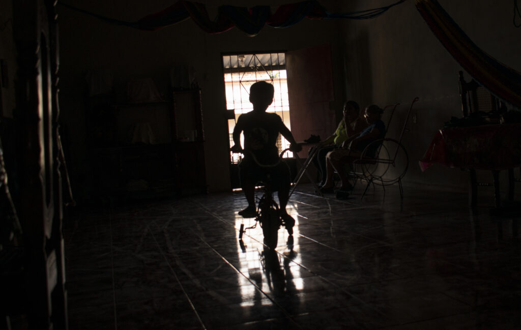 Elián, uno de los huérfanos del régimen de Bukele, cambia en un triciclo por su casa. 