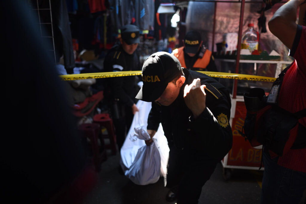 Un policía carga el cadaver de una mujer luego de ser asesinada en un mercado de zona 18 en la Ciudad de Guatemala el 2 de diciembre de 2018. (Foto/Edwin Bercián)