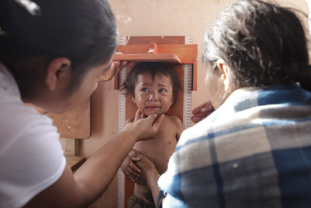 Niña llora mientras le realizan tallaje por bajo peso en Guatemala. Foto: Edwin Bercián